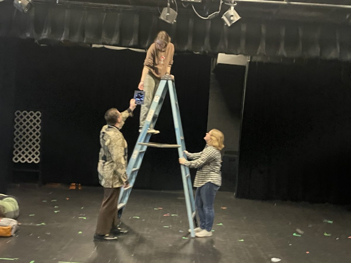 Theatre members fix the lighting above the stage for their next performance.